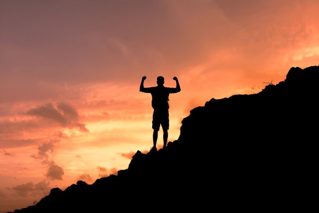 A determined man standing on a mountain peak at sunrise, representing motivation and success.